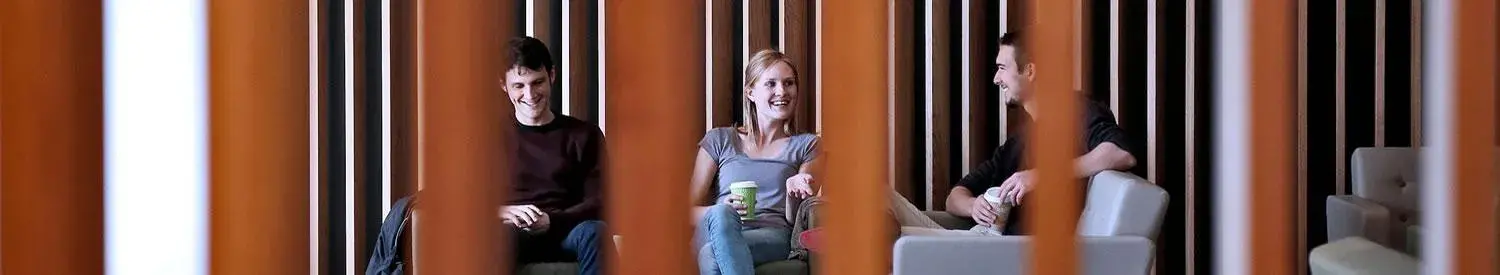 Three students seated while talking to each other.